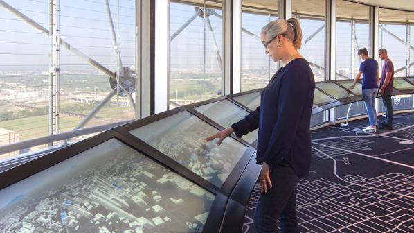 A visitor interacts with the observation deck touchscreen on Reunion Tower's GeO-Deck.